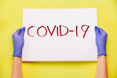 COVID-19 Coronavirus yaratıcı kavramı. Eldivenli eller COVID 19 'un posterini tutuyor. Üst manzara, düz uzanma.