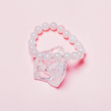 rose quartz semiprecious bracelet on pink background. Creative bijouterie concept. clipart