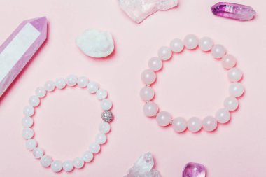 rose quartz semiprecious bracelet on pink background. Creative bijouterie concept. clipart