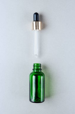 Cilt Bakımı, kozmetik için ambalaj minimalist fotoğraf. Pastel renklerde bir pipet ile yeşil cam şişe. Düz yatıyordu.