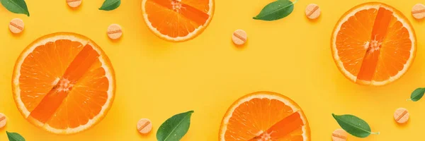 Creativa composición de fondo de verano con rodajas de naranja y vinamina C, pastillas, hojas sobre un fondo amarillo. Concepto de salud mínima —  Fotos de Stock