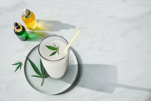 大麻牛奶、大麻叶和一瓶头皮油和药水放在厨房桌子上。 顶视图，平铺复制空间 — 图库照片