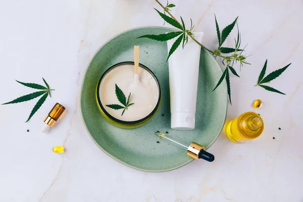 Kosmetika med cannabis olja på en turkos platta på en ljus marmor bakgrund. Kopiera mellanslag, utkast. — Stockfoto