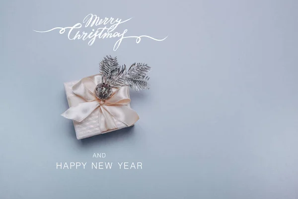 Christmas composition.Small gift box with Christmas decor, a spruce silver branch on a light blue background. Minimalism, flat lay. Copy space. — Stock Photo, Image