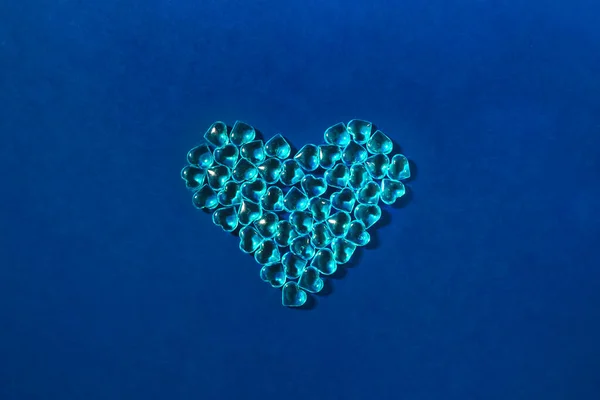 Heart shape made of glass blue hearts on a blue background. Minimal love concept — 스톡 사진