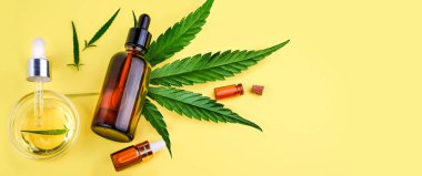 Cbd, kenevir yağı, Thc tentürü ve sarı arka planda kenevir yapraklı cam şişeler.