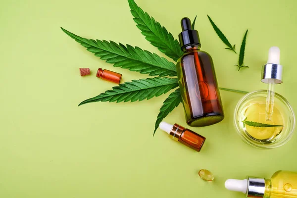 Glass bottles with CBD, hemp oil, THC tincture and hemp leaves on yellow background — Stock Photo, Image