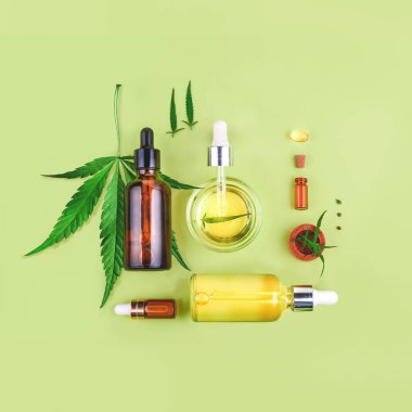 Cbd yağlı cam şişeler, Thc tentür ve yeşil arka planda kenevir yaprakları. Düzlük, minimalizm. Kozmetik Cbd kenevir yağı.
