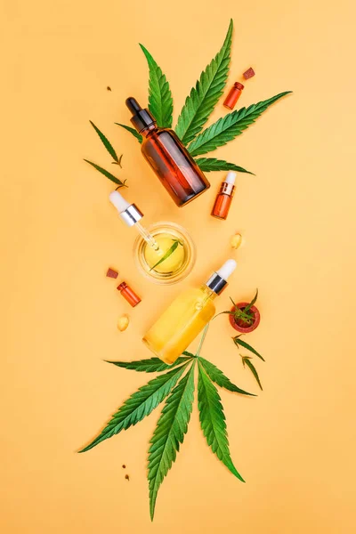 Glasflaskor med Cbd olja, Thc tinktur och hampa blad på gul bakgrund. minimalism. Kosmetika Cbd hampaolja — Stockfoto