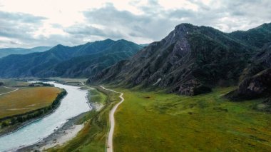 Dağ sıraları boyunca nehrin yanındaki yol. İnsansız hava aracının dağ manzarası. Altai.