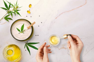 CBD kozmetik yağlı bir boru, kadın ellerinde kozmetik ürünler, esrar ve kenevir yapraklı krem, marihuana