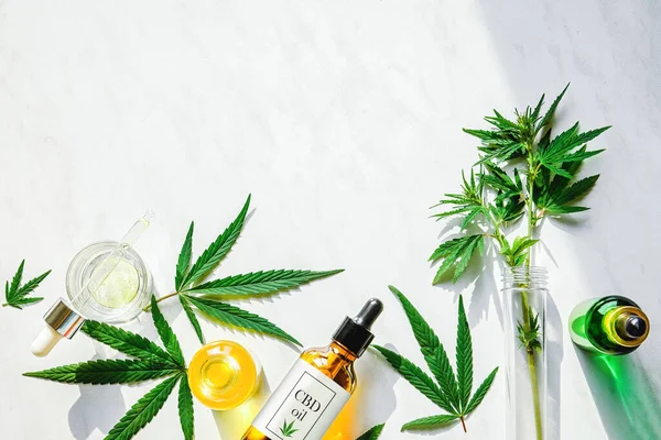 CBD yağlı çeşitli cam şişeler, THC tentür ve mermer zemin üzerinde marihuana yaprakları. Düzlük, minimalizm. Kozmetik CBD yağı