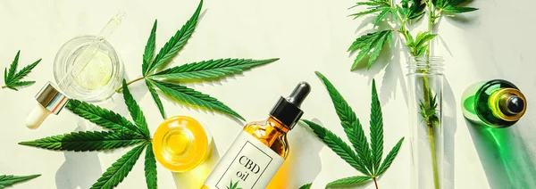 Различные стеклянные бутылки с маслом CBD, настойка THC и листья конопли на мраморном фоне. Плоский пол, минимализм. Косметическое масло CBD — стоковое фото