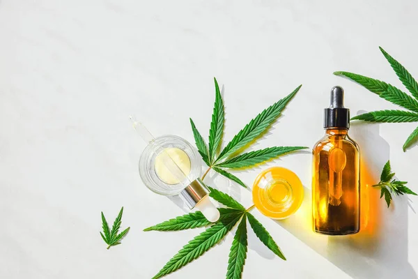 Glass brown bottle with cannabis CBD oil and hemp leaves on a marble background. Copy space — Stock Photo, Image