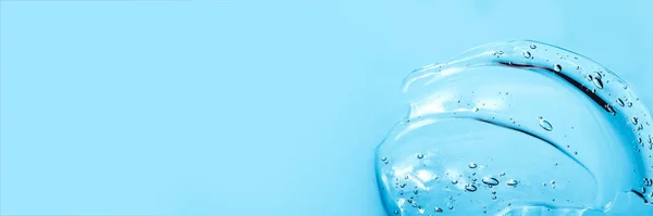 Kosmetický gel kyseliny hyaluronové. Gelová textura s bublinami na modrém pozadí. Průhledný nátěr gelu Banner — Stock fotografie