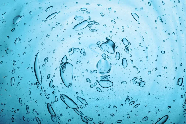 Textura de água com bolhas Gel cosmético de ácido hialurônico. Textura de gel com bolhas em um fundo azul . — Fotografia de Stock