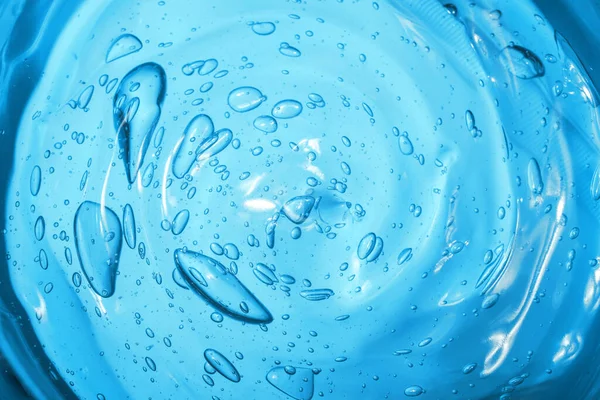 Gel cosmético de ácido hialurônico. Textura de gel com bolhas em um fundo azul. Esfregaço transparente de gel — Fotografia de Stock