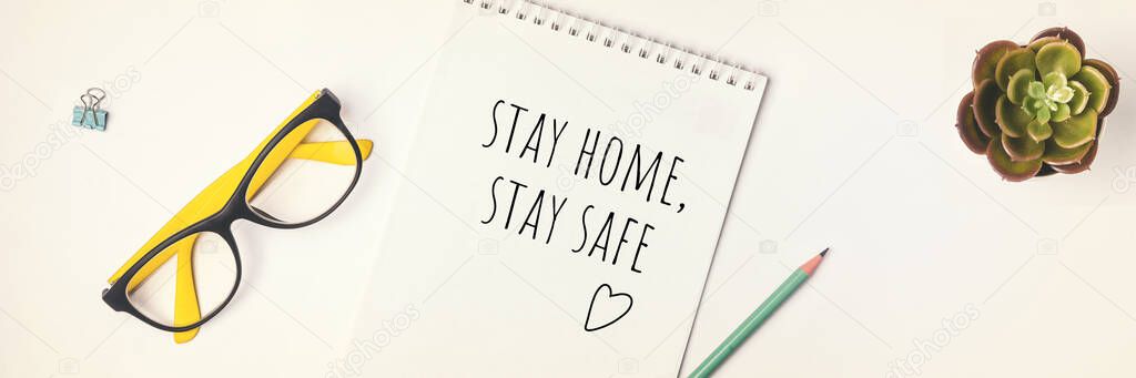 Words stay home, stay safe written in notebook, concept of self quarantine at home as preventative virus Flat lay Banner