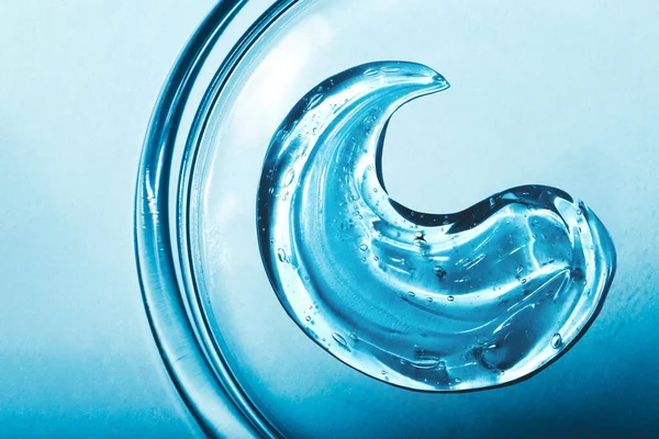 Textura de ácido hialurônico, gel de soro. Esfregaço transparente de gel isolado sobre fundo azul — Fotografia de Stock