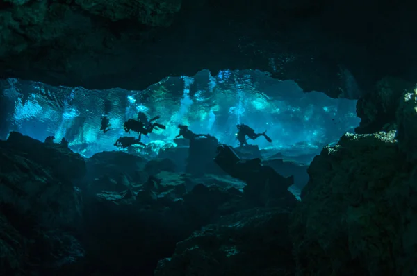 Fisk skål (en grupp dykare simmar i vatten av undervattens grotta) — Stockfoto