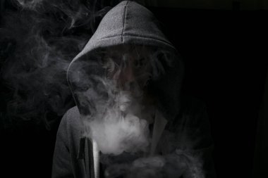 vaping adam yasaktır bulutlar dolu bir hoody giyiyor. 