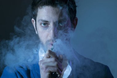 Elektronik sigara tutan karanlık bir arka plan üzerinde izole genç adam