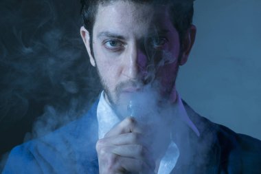 Elektronik sigara tutan karanlık bir arka plan üzerinde izole genç adam