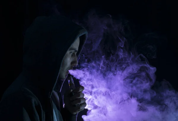 Homem vape um cigarro eletrônico com muita fumaça . — Fotografia de Stock