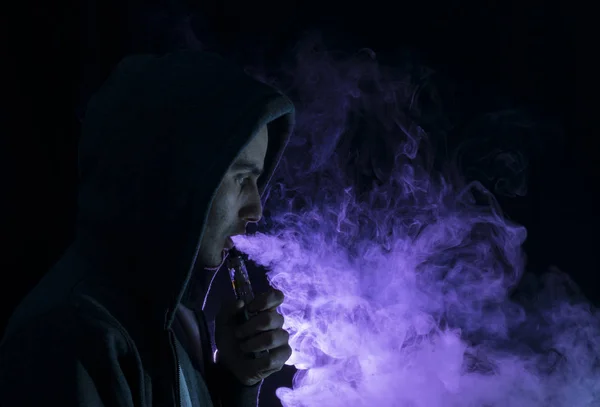 Homme vape une cigarette électronique avec beaucoup de fumée . — Photo