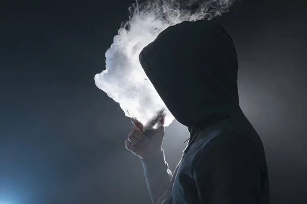 Mann zündet sich eine elektronische Zigarette mit viel Rauch an. — Stockfoto