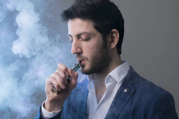 Homme vape une cigarette électronique avec beaucoup de fumée . — Photo