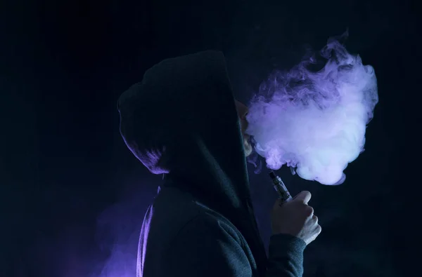 Uomo vaporizzare una sigaretta elettronica con un sacco di fumo . Immagine Stock