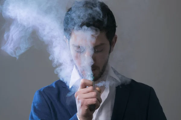 Uomo vaporizzare una sigaretta elettronica con un sacco di fumo . Foto Stock Royalty Free