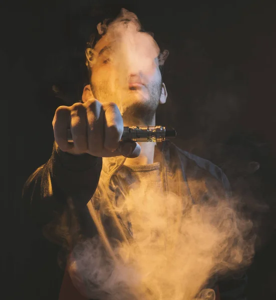 Aislado hombre vapeo e cigarrillo sobre un fondo oscuro — Foto de Stock