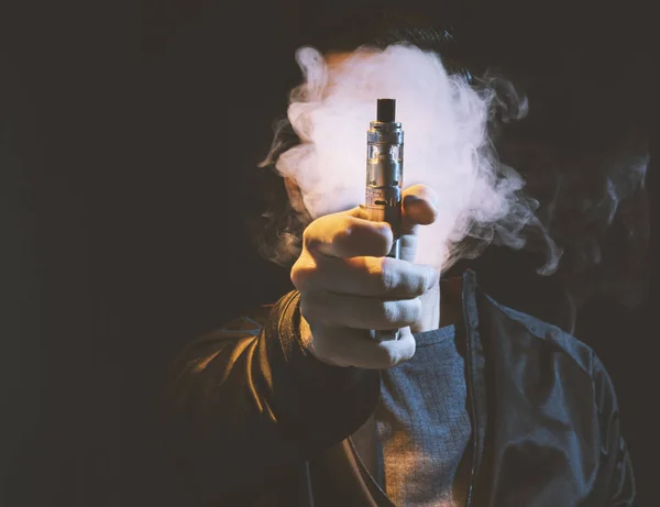 Isolierter Mann verdampft E-Zigarette vor dunklem Hintergrund — Stockfoto