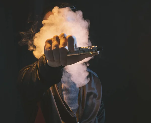 Изолированный человек, испаряющий сигарету на темном фоне — стоковое фото