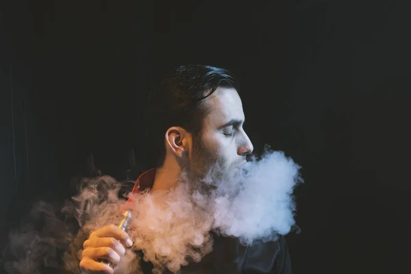 Homme isolé vapotage e cigarette sur un fond sombre — Photo