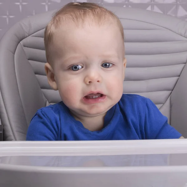 Расстроенный маленький ребенок в детском кресле смотрит в камеру — стоковое фото
