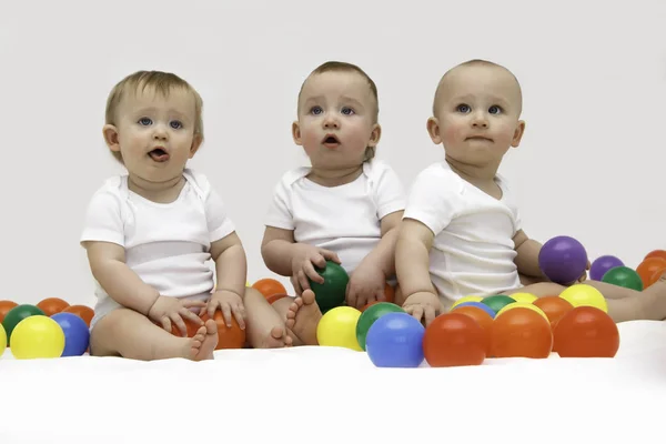 Baby triplets engaged and playing with colorful balls — Stock Photo, Image