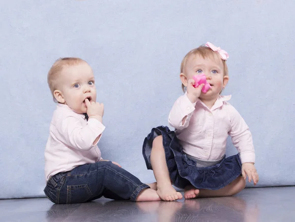 Härlig spädbarn pojke och funny baby flicka sitter på golvet och tittar på kameramannen — Stockfoto