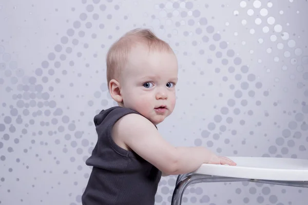 Misstänkta spädbarn pojke lutar på den vita stolen — Stockfoto