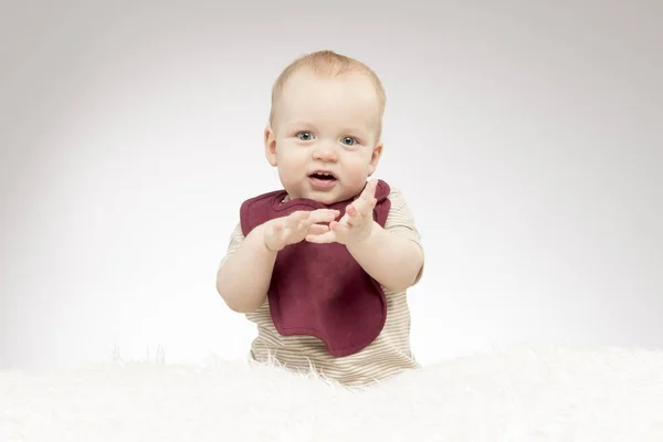 Söt liten pojke ler, sitter på det vita täcket och titta på kameran. Koncept för gratulationskort — Stockfoto