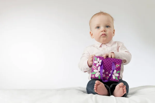 Allvarlig pojke håller några närvarande i hans armar. Tankeväckande spädbarn kid med en gåva. Kopiera utrymme. Redo vykort — Stockfoto