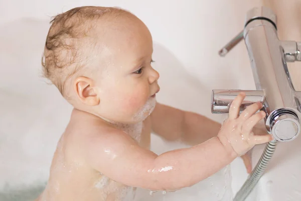 Серйозний 11-місячний хлопчик відкриває кран. Немовля в пінопласті, що досліджує систему водопостачання — стокове фото