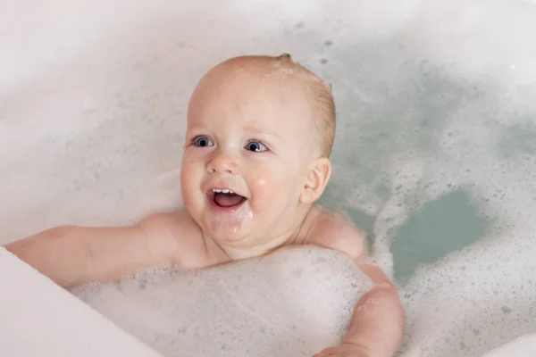 Adorable baby blue-eyed boy gra w wannie. Śliczne niemowlę noworodek kąpiel w wannie — Zdjęcie stockowe