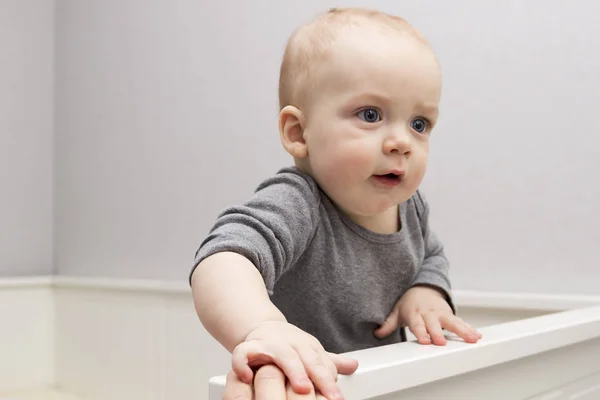 Cute baby boy in a crib. Adorable infant kid staying in a cot. — Stock Photo, Image