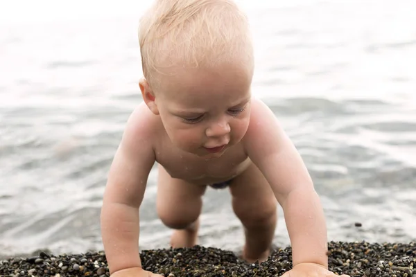 Evolutie. Van de zee naar de kust. Schattige babyjongen kruipen naar de wal — Stockfoto