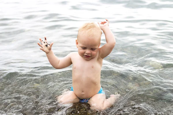 Schattige babyjongen spatten in de golven van de zee — Stockfoto