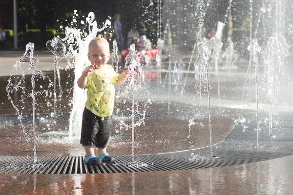 Забавный малыш в фонтане. Милый мальчик веселится и прячется в фонтане. . — стоковое фото