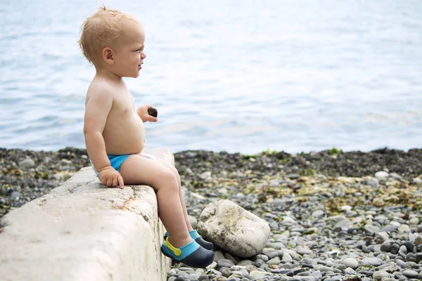 Ładny maluch siedzi na parapet kamienia nad brzegiem morza. Miejsce — Zdjęcie stockowe